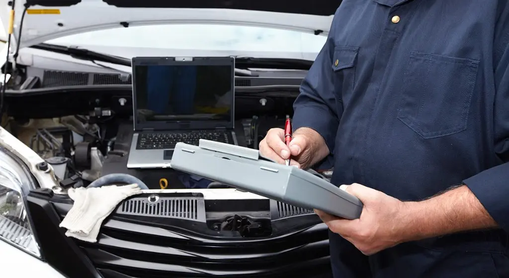 Diagnosis del coche con el equipo y un portátil sobre el motor